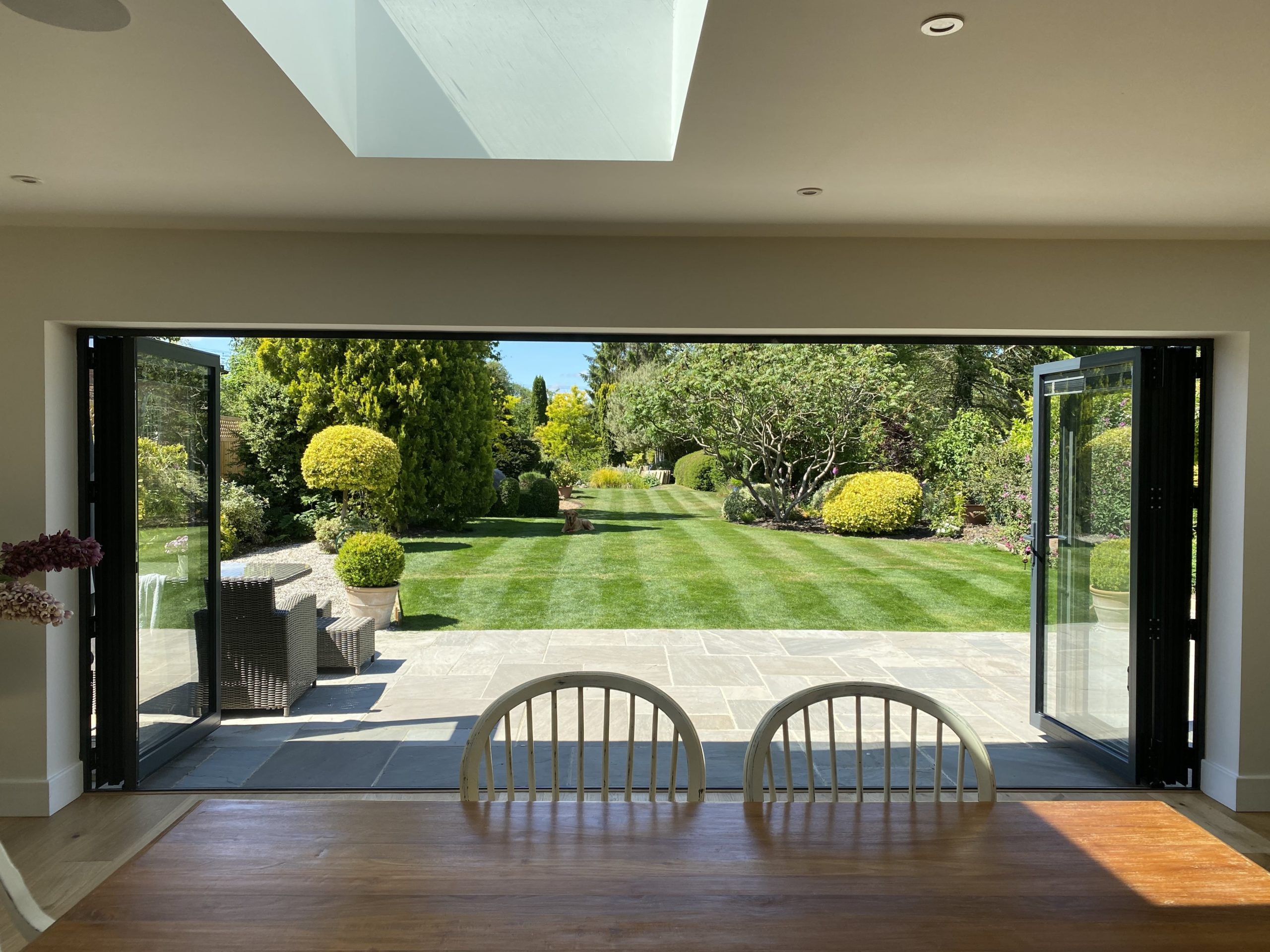 alutech bf73 bifold doors open over a lawn